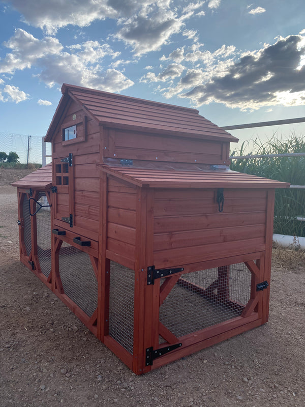 A red wooden chicken coop for 4+ chickens set outdoors with a partly cloudy sky in the background.